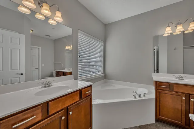 a bathroom with a tub a double vanity sink and a mirror