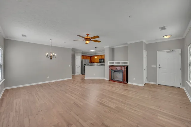 an empty room with wooden floor and kitchen view