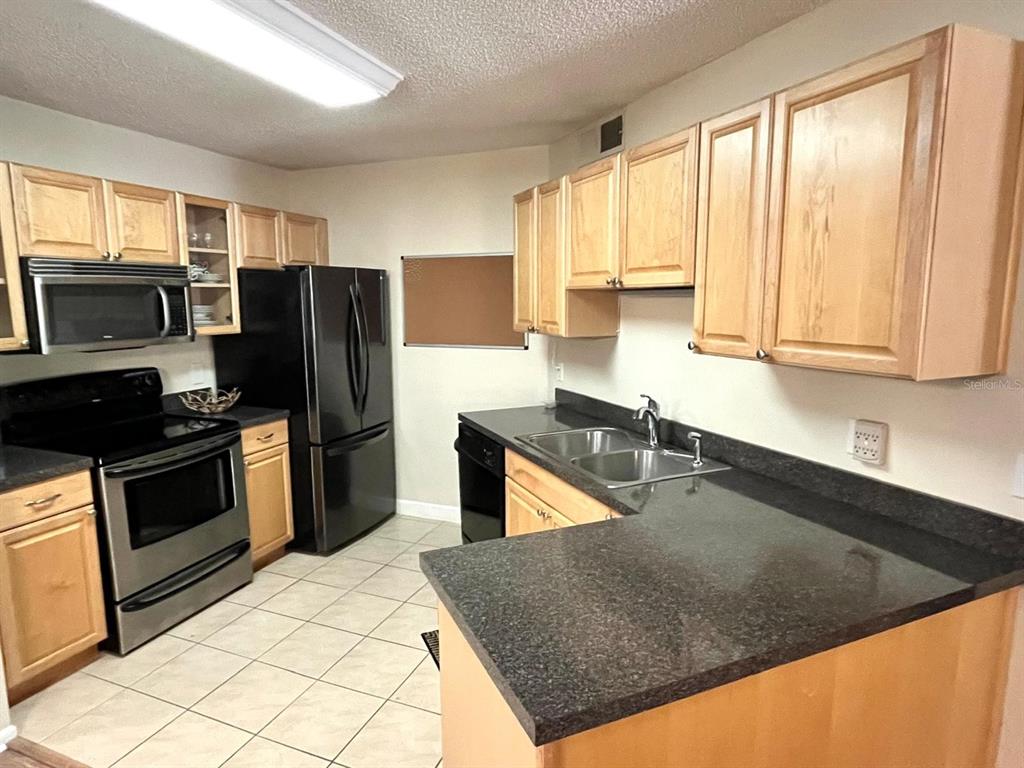1550 South Belcher Road, Unit 524 Clearwater, FL 33764 - Photo 8 of 45 a kitchen with stainless steel appliances granite countertop a refrigerator a stove and a sink with wooden cabinets