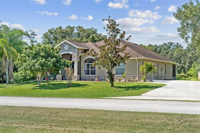 a view of a house with a big yard and large trees