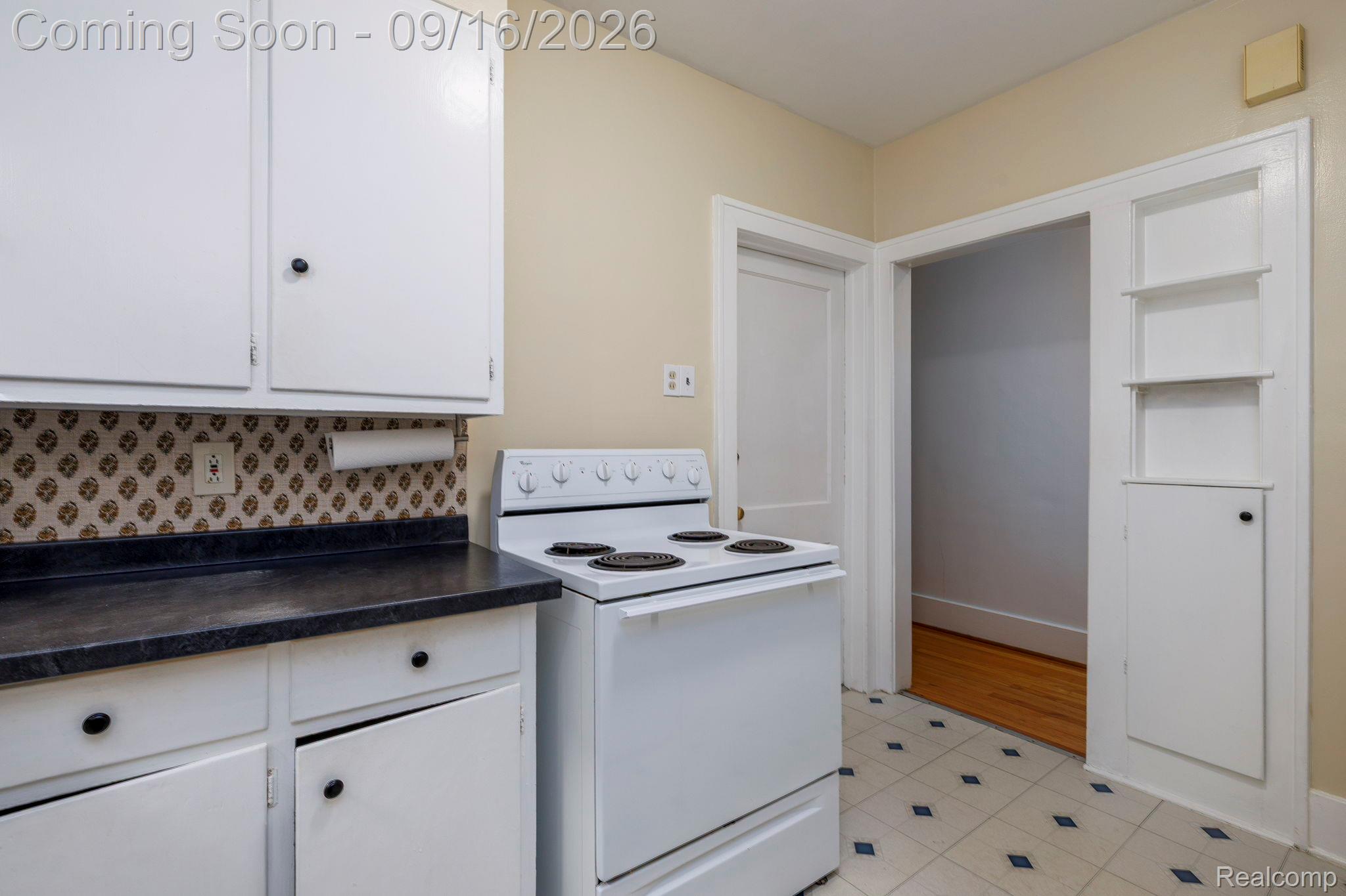 999 Nottingham Road Grosse Pointe, MI 48230 - Photo 17 of 30 White cabinetry with dark hardware, dark countertops, patterned backsplash, and built-in shelving