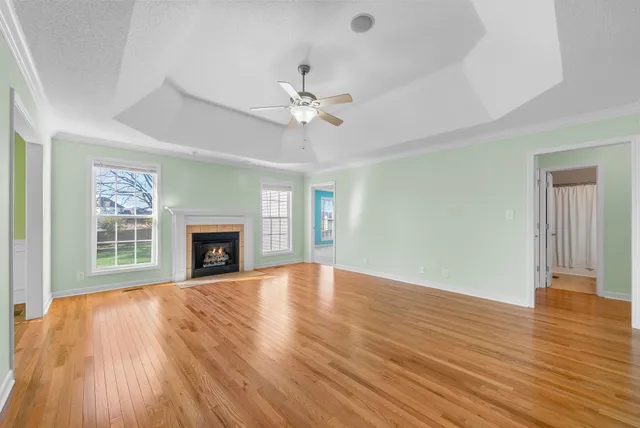 an empty room with wooden floor fireplace and fan