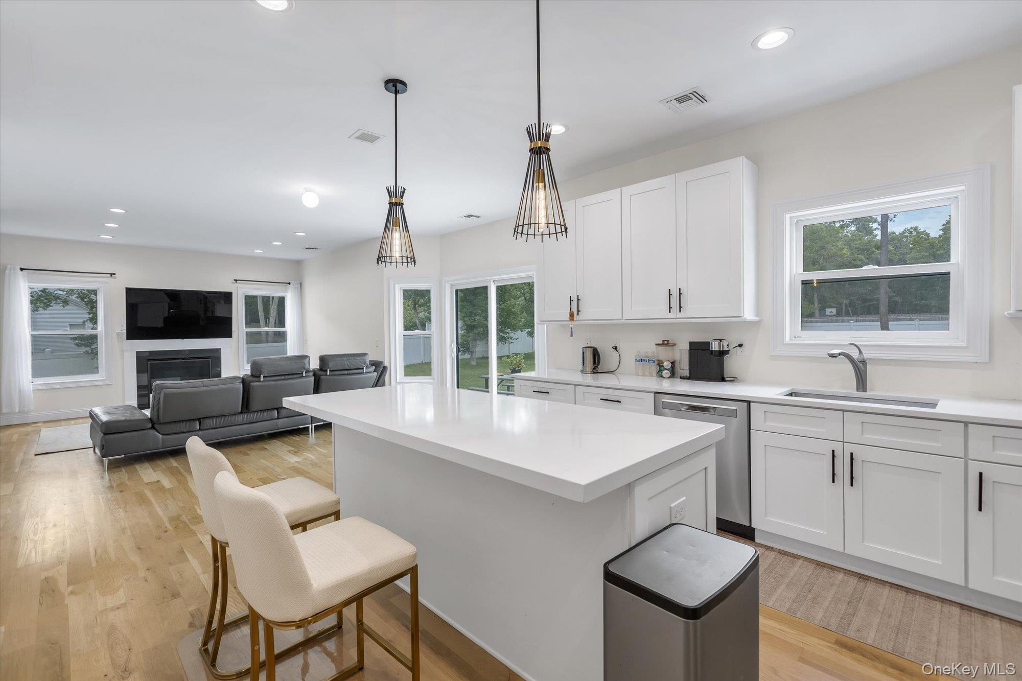 135 Elizabeth Way Ridge, NY 11961 - Photo 7 of 24 a large white kitchen with a stove a sink a kitchen island with chairs and wooden floor