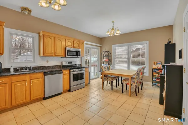 a kitchen with stainless steel appliances granite countertop a stove top oven a sink dishwasher a dining table and chairs with wooden floor