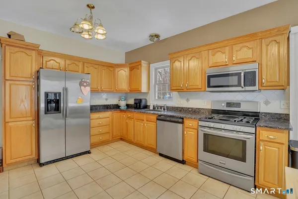 a kitchen with stainless steel appliances granite countertop a stove top oven a refrigerator and a sink