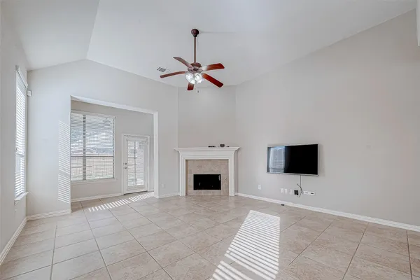 a view of an empty room with window and chandelier fan