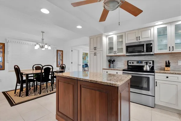 a kitchen with stainless steel appliances granite countertop a stove a sink a microwave a dining table and chairs