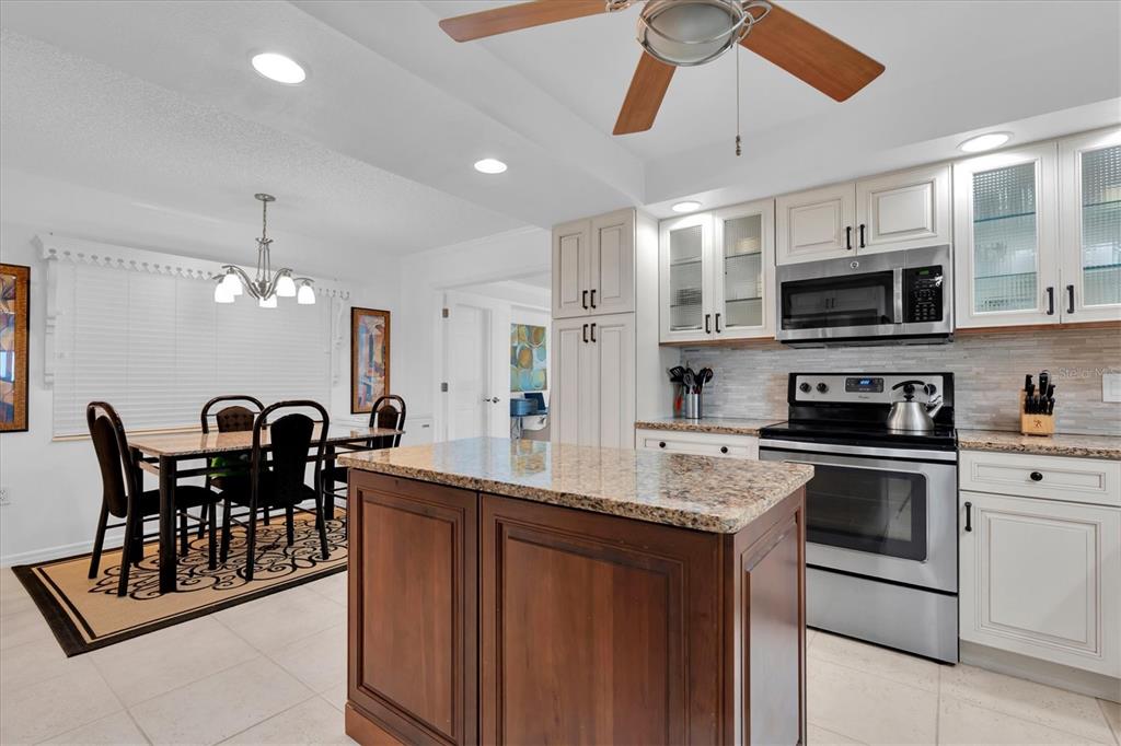 6500 Sunset Way, Unit 316 St. Pete Beach, FL 33706 - Photo 15 of 58 a kitchen with stainless steel appliances granite countertop a stove a sink a microwave a dining table and chairs