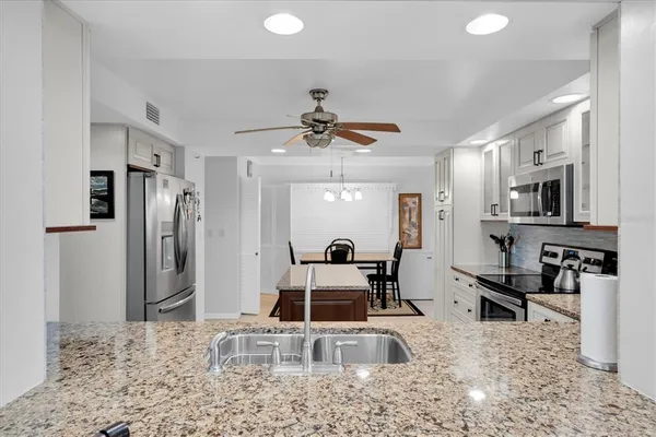 a kitchen with stainless steel appliances granite countertop a sink refrigerator and cabinets
