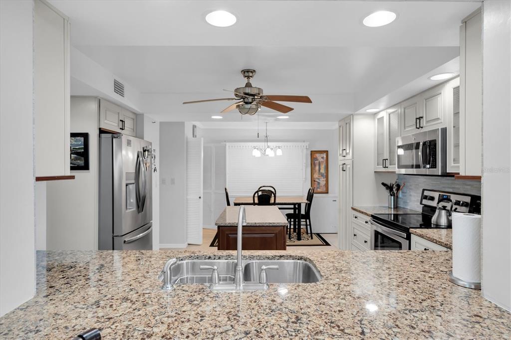 6500 Sunset Way, Unit 316 St. Pete Beach, FL 33706 - Photo 17 of 58 a kitchen with stainless steel appliances granite countertop a sink refrigerator and cabinets