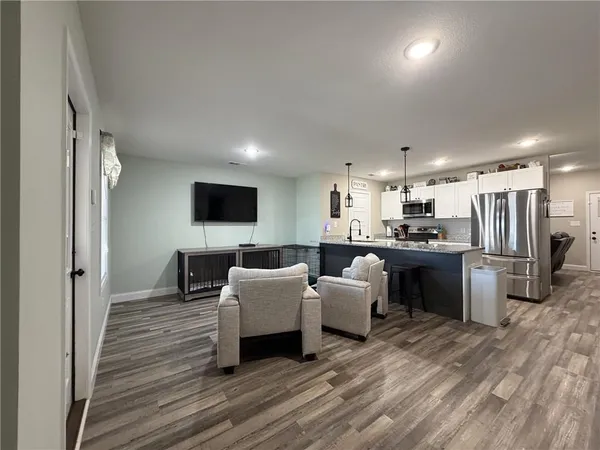 a living room with stainless steel appliances furniture and a flat screen tv