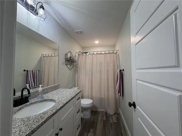 a bathroom with a granite countertop sink toilet and shower a mirror