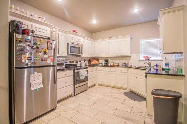 a kitchen with stainless steel appliances granite countertop a refrigerator sink and wooden cabinets