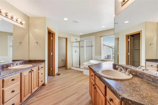 a bathroom with a granite countertop double vanity sink a mirror and a shower