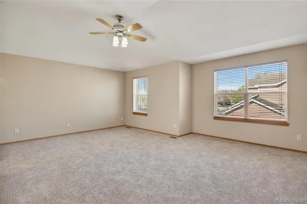 an empty room with windows and ceiling fan