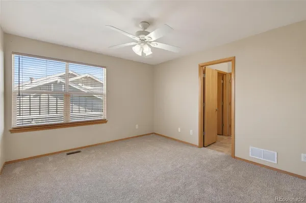 an empty room with chandelier fan and windows
