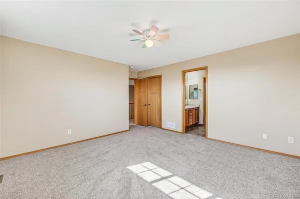 an empty room with closet and a chandelier fan