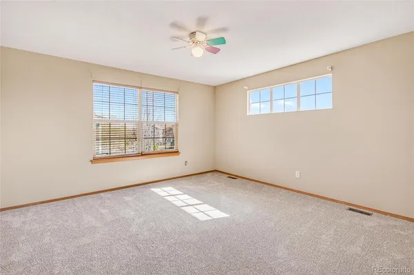 an empty room with windows and fan