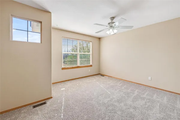 an empty room with windows and fan