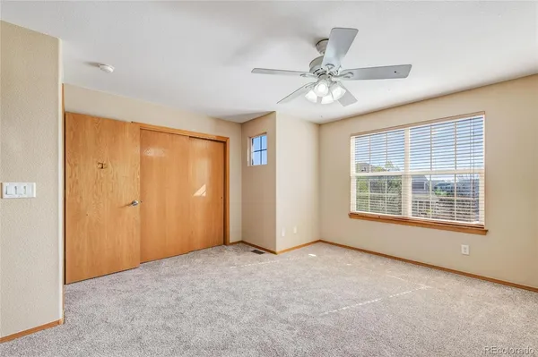 an empty room with chandelier fan and windows