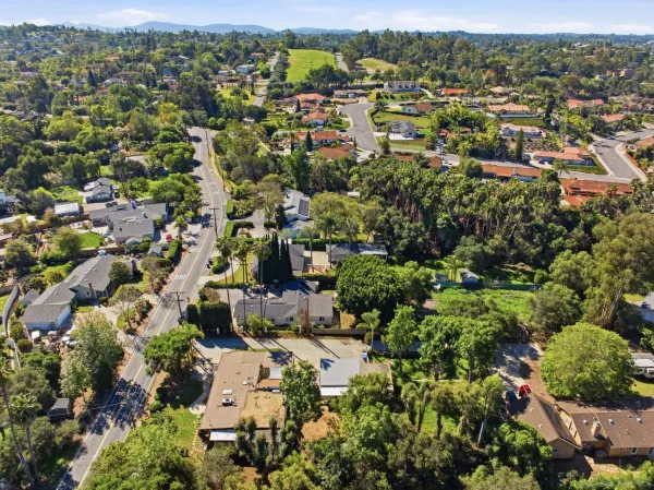 an aerial view of residential houses with outdoor space and trees