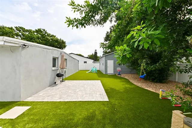 a view of a yard in front of a house with plants and large tree