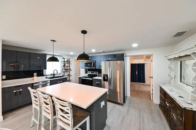 a kitchen with stainless steel appliances a dining table chairs stove and refrigerator