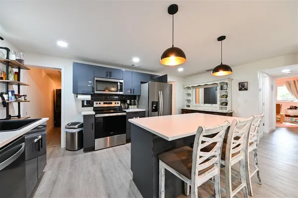 a kitchen with a chandelier stainless steel appliances and cabinets