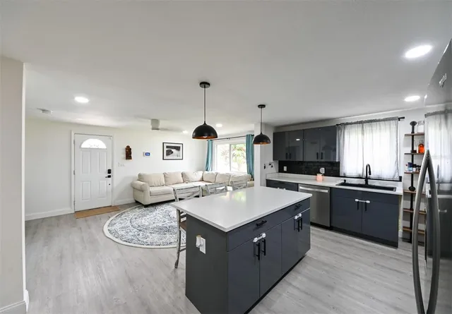 a large kitchen with stainless steel appliances granite countertop a stove a sink dishwasher and a refrigerator with wooden floor