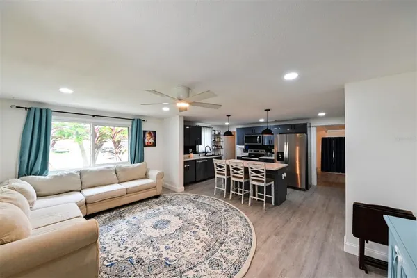 a living room with furniture kitchen view and a large window