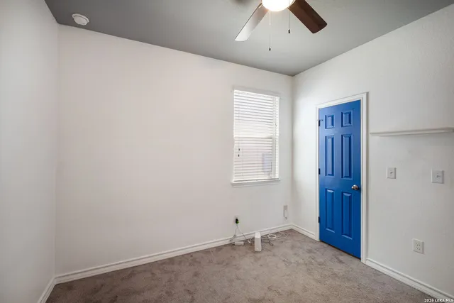 an empty room with a window and a fan