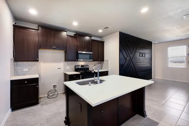 a kitchen with kitchen island a sink refrigerator and microwave