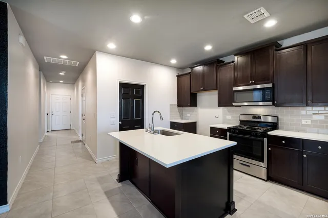 a kitchen with kitchen island granite countertop stainless steel appliances lots of counter top space sink refrigerator and cabinets