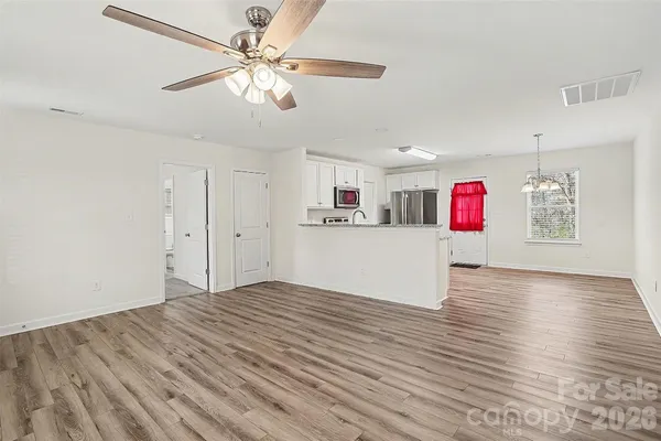 a view of a kitchen with wooden floor and ceiling fan