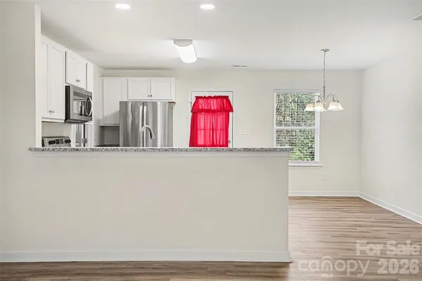 a view of kitchen with stainless steel appliances granite countertop cabinets and a wooden floor