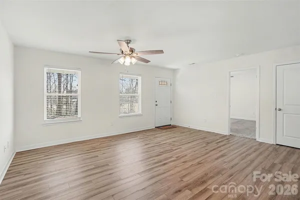 a view of an empty room with wooden floor and a window