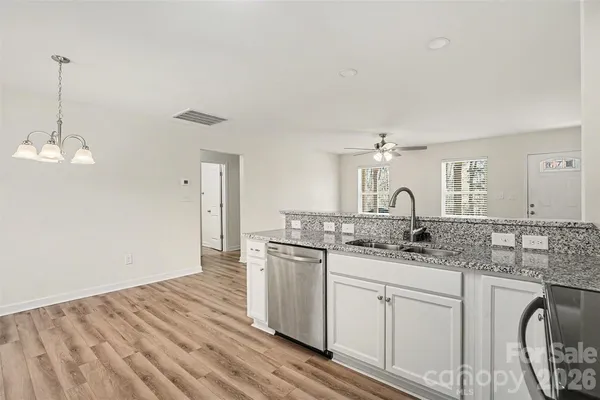 a kitchen with stainless steel appliances granite countertop a sink stove and white cabinets with wooden floor
