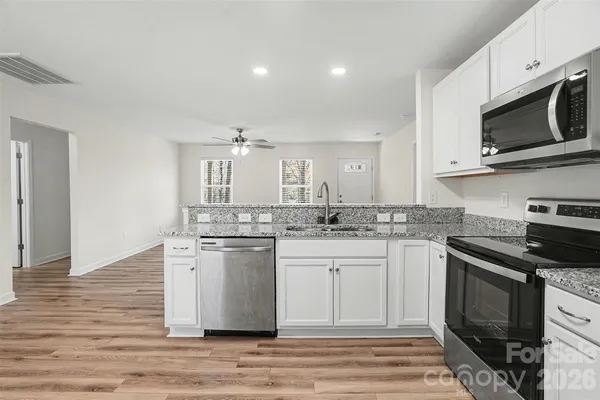 a kitchen with stainless steel appliances granite countertop a stove top oven microwave and cabinets