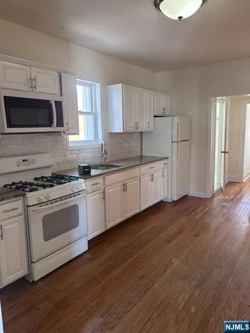 a kitchen with granite countertop a stove a sink and a microwave