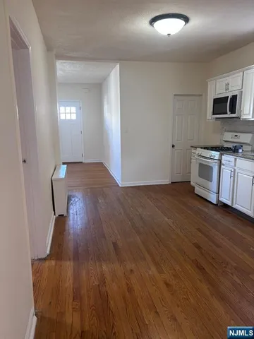 a view of a kitchen with wooden floor and electronic appliances