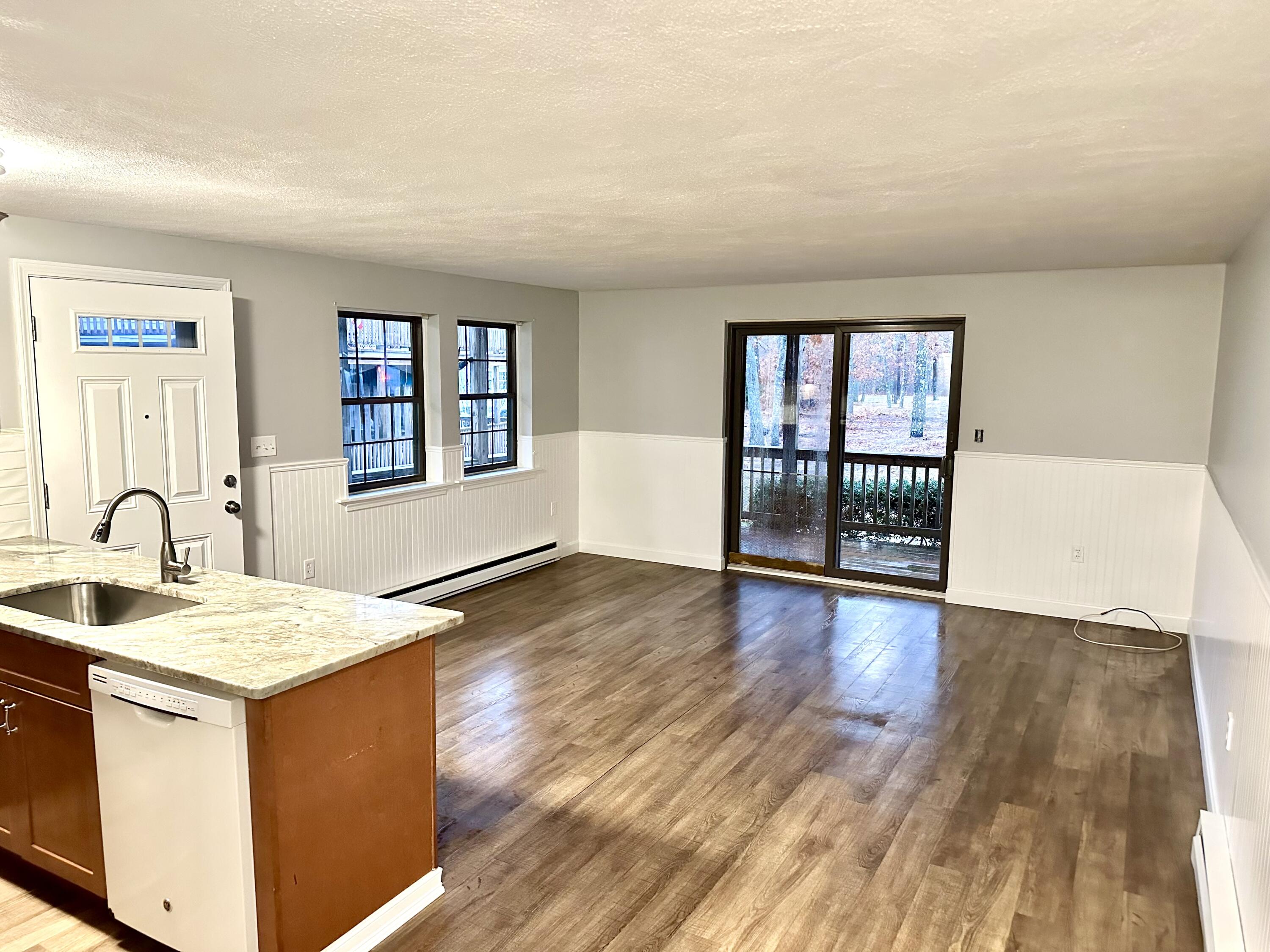 35 Ashumet Road, Unit 10B Mashpee, MA 02649 - Photo 4 of 7 a view of an empty room with a kitchen and wooden floor