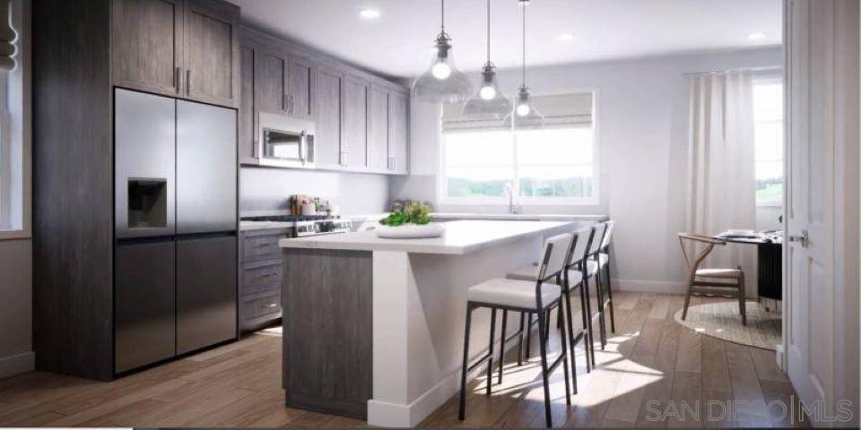 a kitchen with stainless steel appliances a dining table chairs refrigerator and cabinets