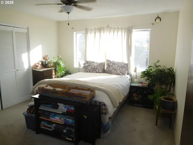 a bedroom with a bed table chair and a window