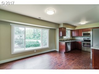 13240 Southeast Rusk Road Milwaukie, OR 97222 - Photo 7 of 24 a kitchen with stainless steel appliances granite countertop a refrigerator a sink a stove a microwave oven with a dining table and chairs