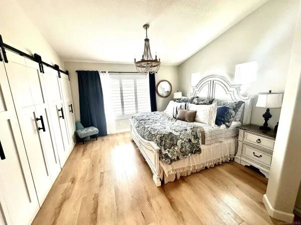 a spacious bedroom with a bed a dresser and floor to ceiling window
