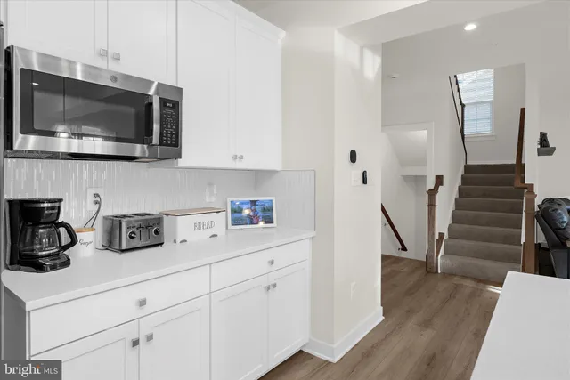 a kitchen with stainless steel appliances kitchen island granite countertop a dining table chairs and white cabinets