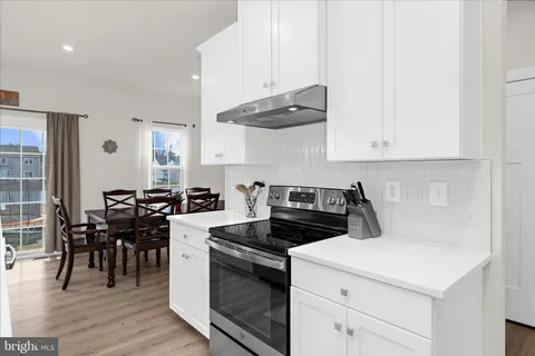 a kitchen with stainless steel appliances kitchen island granite countertop a dining table chairs and white cabinets