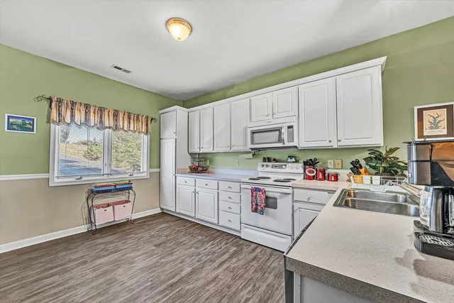 a kitchen with granite countertop white cabinets and white appliances