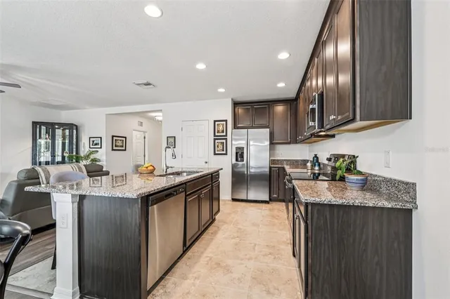 a kitchen with stainless steel appliances granite countertop counter space a sink refrigerator and cabinets