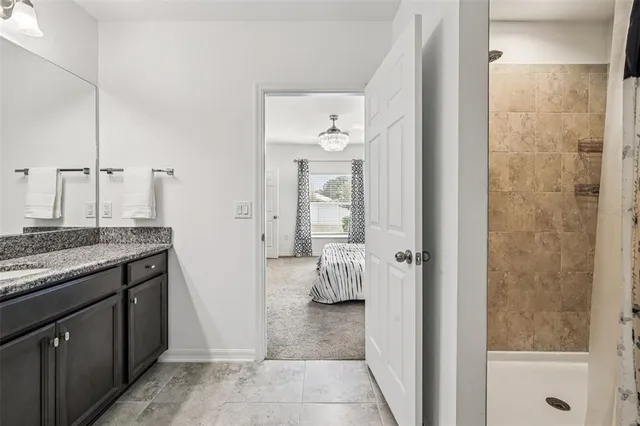 a bathroom with a granite countertop sink a mirror and shower